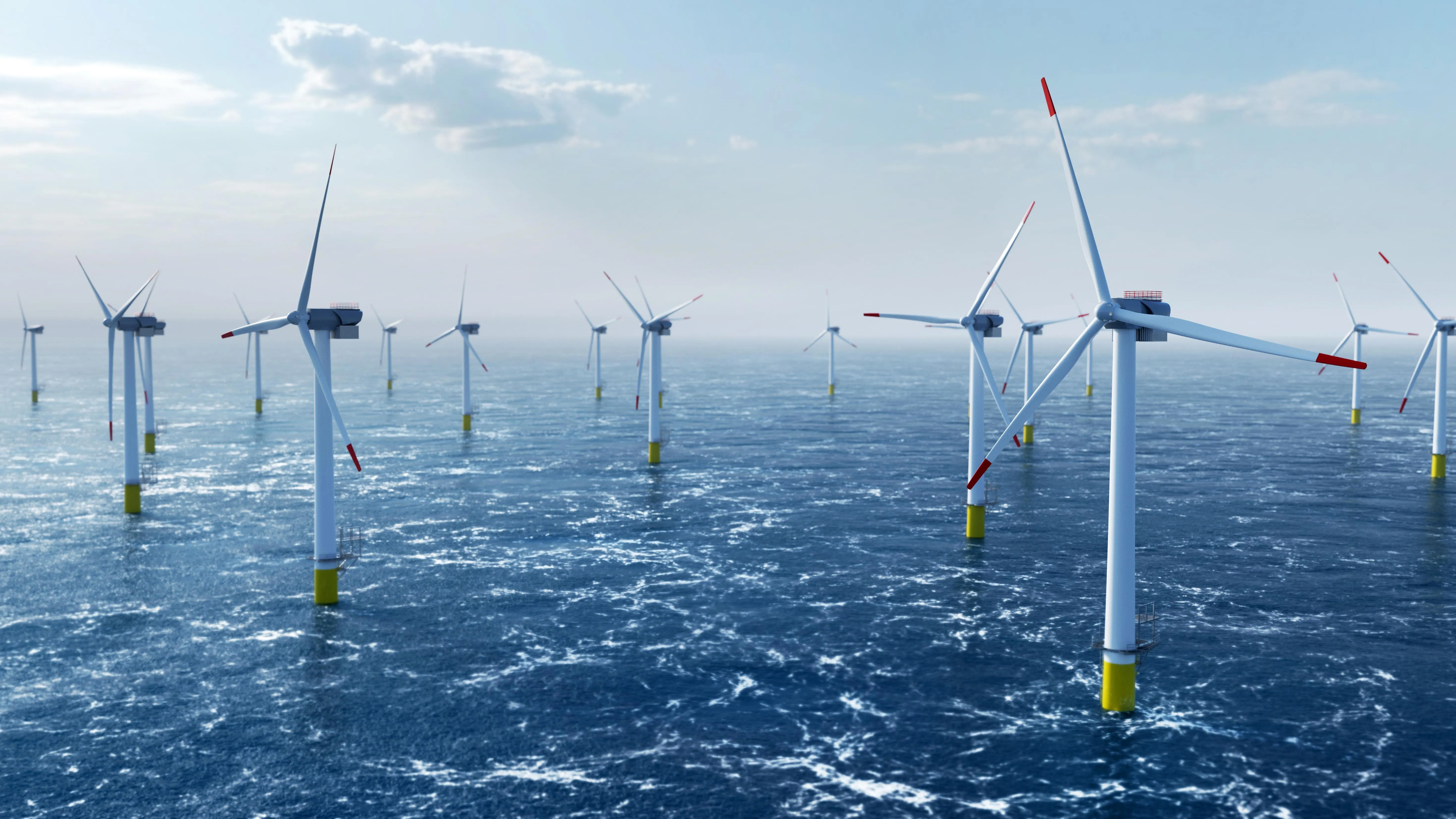 Offshore wind farm with multiple wind turbines in the ocean under a partly cloudy sky.